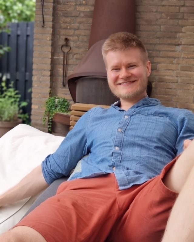Jasper Lammers, smiling, leaning back on an outdoor lounger in a blue shirt